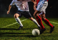 Two soccer players challenging for the ball, low angle view.