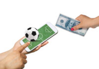 Men hold Mobile to play Football Betting online .